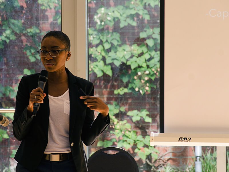 Photo of Talila Lewis standing and holding a mic